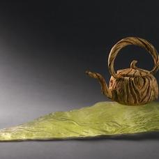 Hand-carved ceramic trompe l'oeil teapot on cast glass stand.