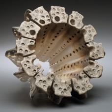 Organic hollow porcelain form with grimy surface accenting the many circular indents covering the piece.