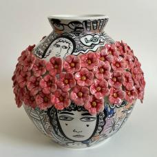 Porcelain vase with ring of red flowes around the widest part. Graphic illustrations with strong black lines fill the rest of the space.