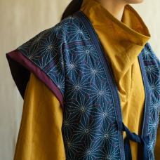 The vest features a star-like flower pattern  hand-stitched on hand-dyed indigo cotton fabric. The brightness and depth of the tunic brings out the strength of the flower stitch. The tunic exhibits hand-stitched designs on natural cotton fabric hand-dyed with turmeric plant.