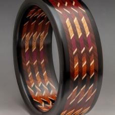 This dramatic and elegant linear Mosaic Bracelet is constructed with 12 different exotic and domestic sustainable hardwoods and Maple veneer. The laminate is cut on the bias a 45 degree angle cut and then the slices are stacked and orientated in a 90 degree rotation captured with Ebony edges.