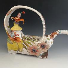 Teapot made with a combination of hand-building and wheel-throwing techniques with painterly glaze and under glaze decoration of flowers. Lid has small flower sculpture.