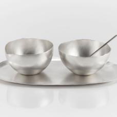 A sugar  creamer  tray  and spoon set. The creamer has a subtle spout included in the form. The vessels and trays were made from hammering flat sheets of silver up into three dimensional forms.