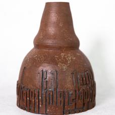 Brown vase with rough textured glaze and inscription along the bottom