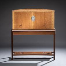 This cabinet features figured English brown oak and a stand of torrified ash. The engraved nickel silver escutcheon plate opens to reveal a detailed interior of holly and ash. In dramatic contrast to the rich tones of the exterior  these naturally light woods illuminate the cabinet from within.