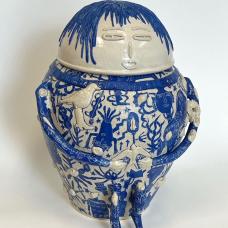 White stoneware sculpture of a sitting human figure covered in bold blue graphic illustrations.