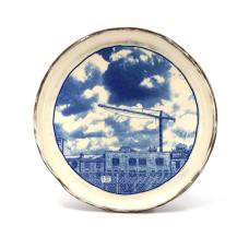 ceramic plate with blue and white picture of a fenced off property and construction crane. 
