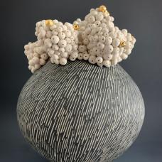 Porcelain vessel topped with clusters of small orbs with accents of  gold luster