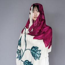 Model draped in large shawl with magenta flower and leaves